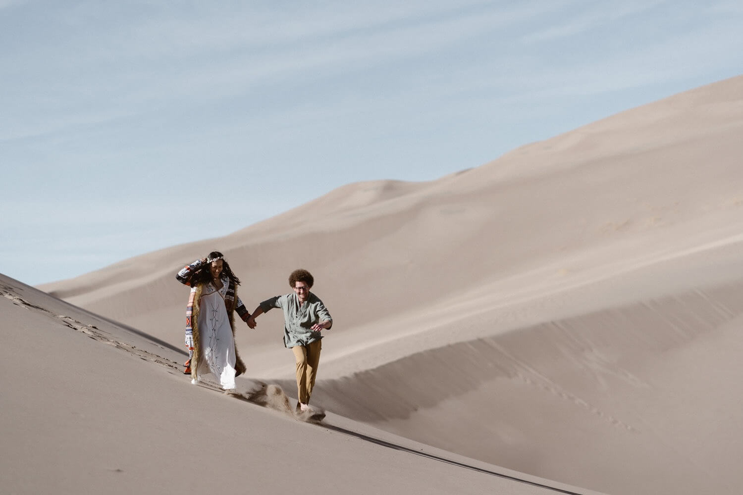 A couple running through the sand at the Great Sand Dunes National Park during their Colorado elopement.