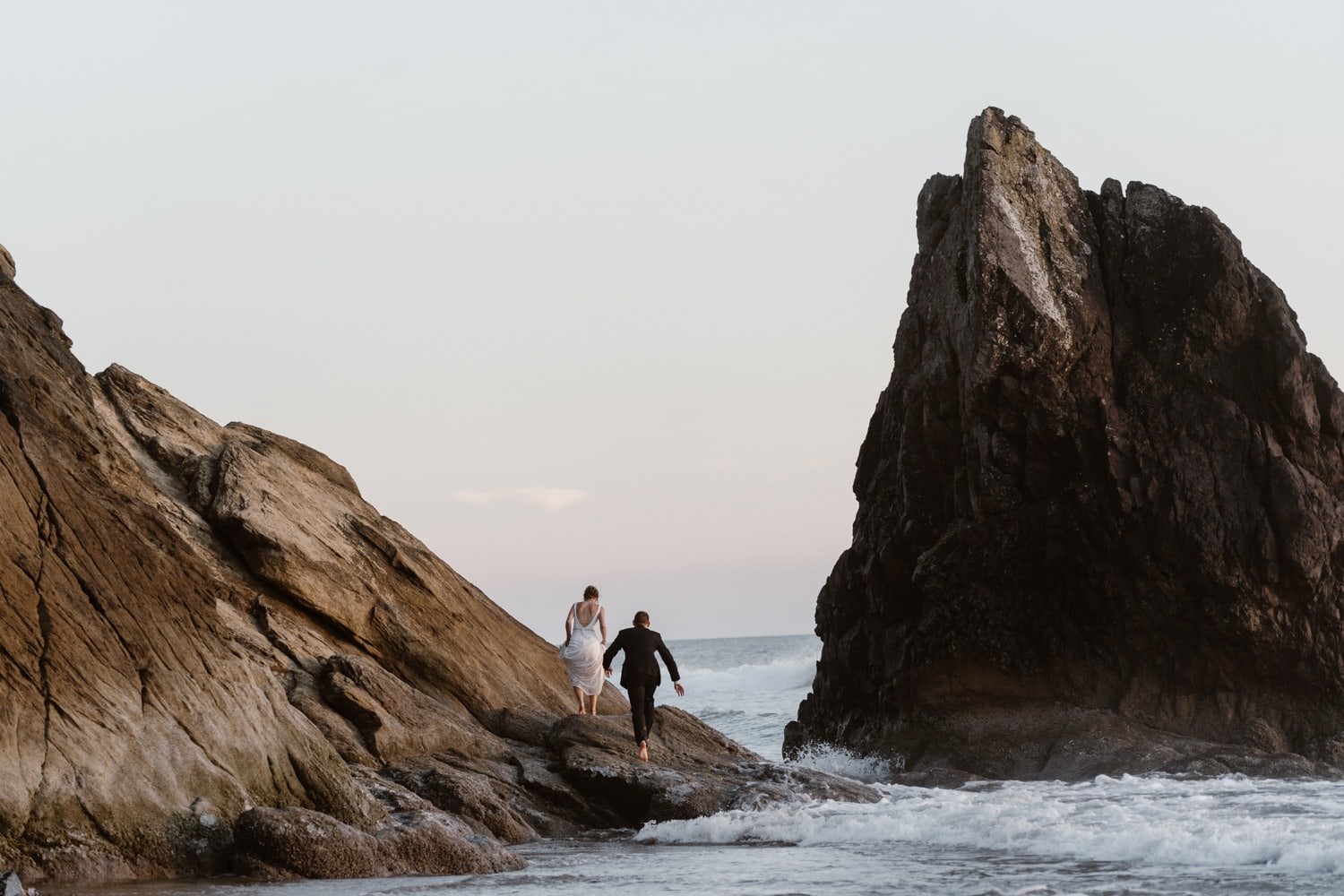 Bride and Groom climbing rock at Hug Point & Cannon Beach Elopement