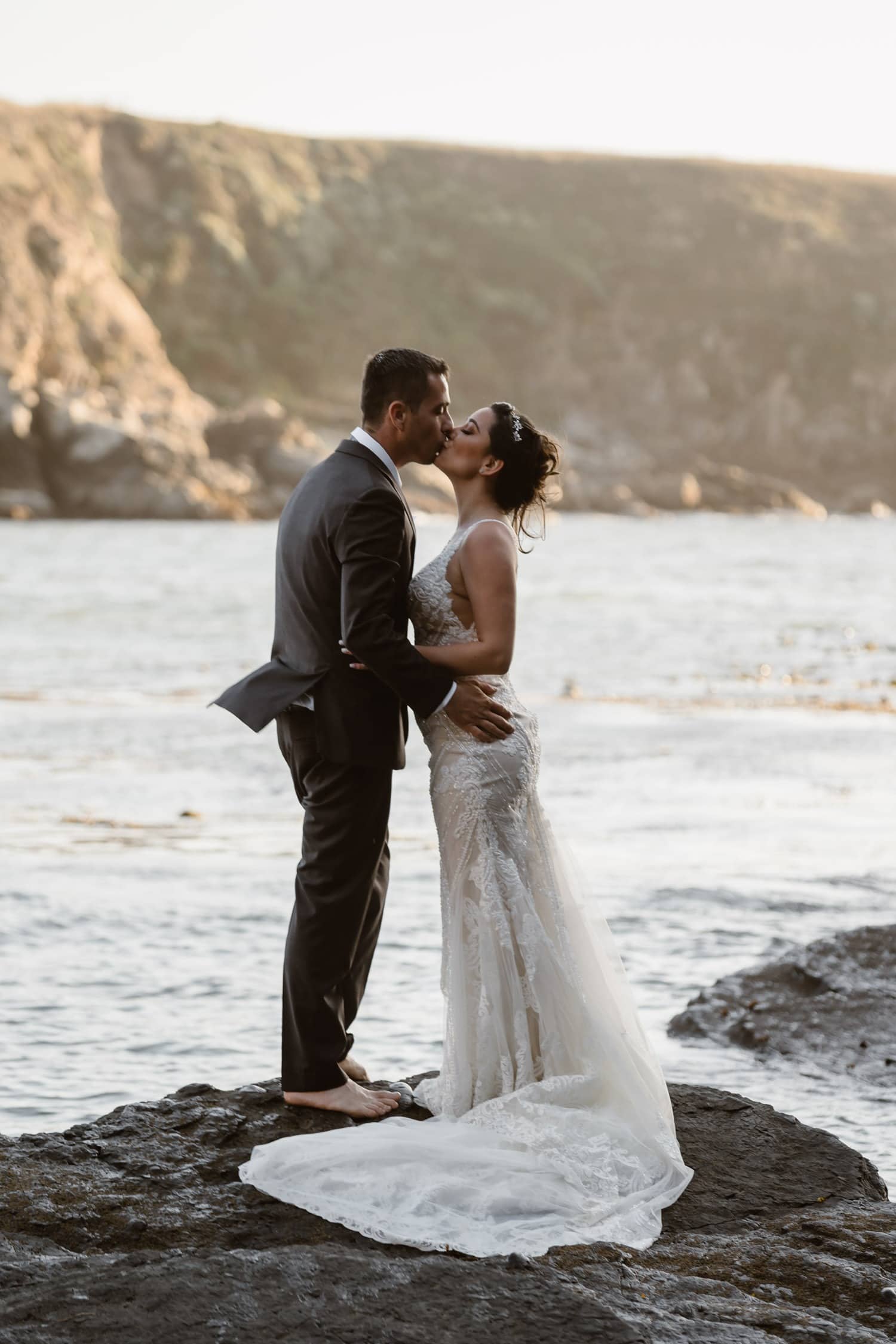 Bride and Groom kissing on rock in ocean at Big Sur Elopement