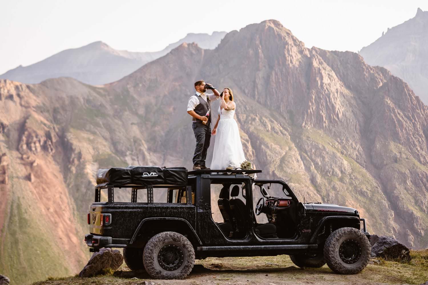 A couple drinking champagne out of horns on top of a jeep during their elopement in Colorado.