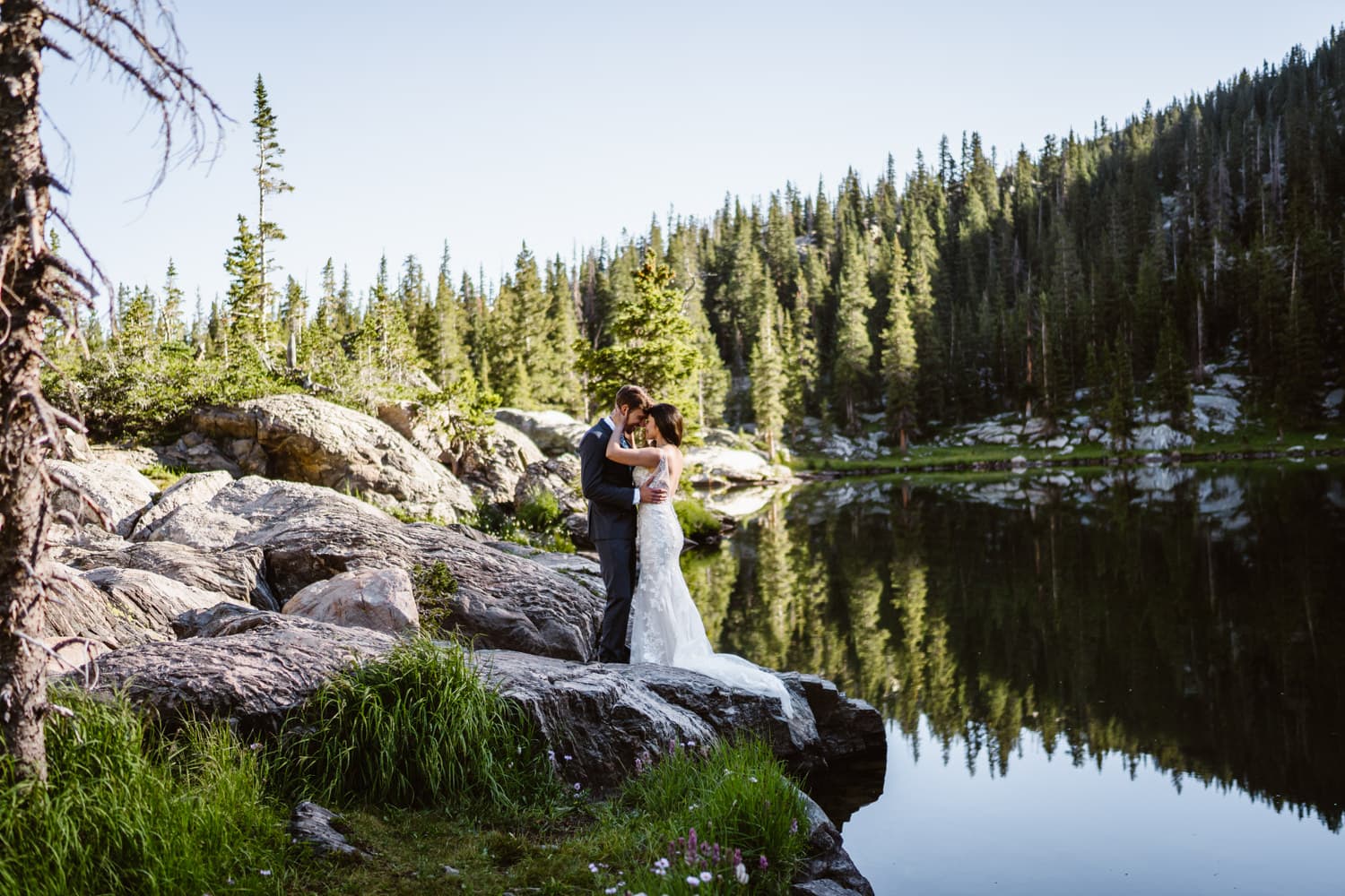 A couple shares an intimate moment with alpine lake reflections.