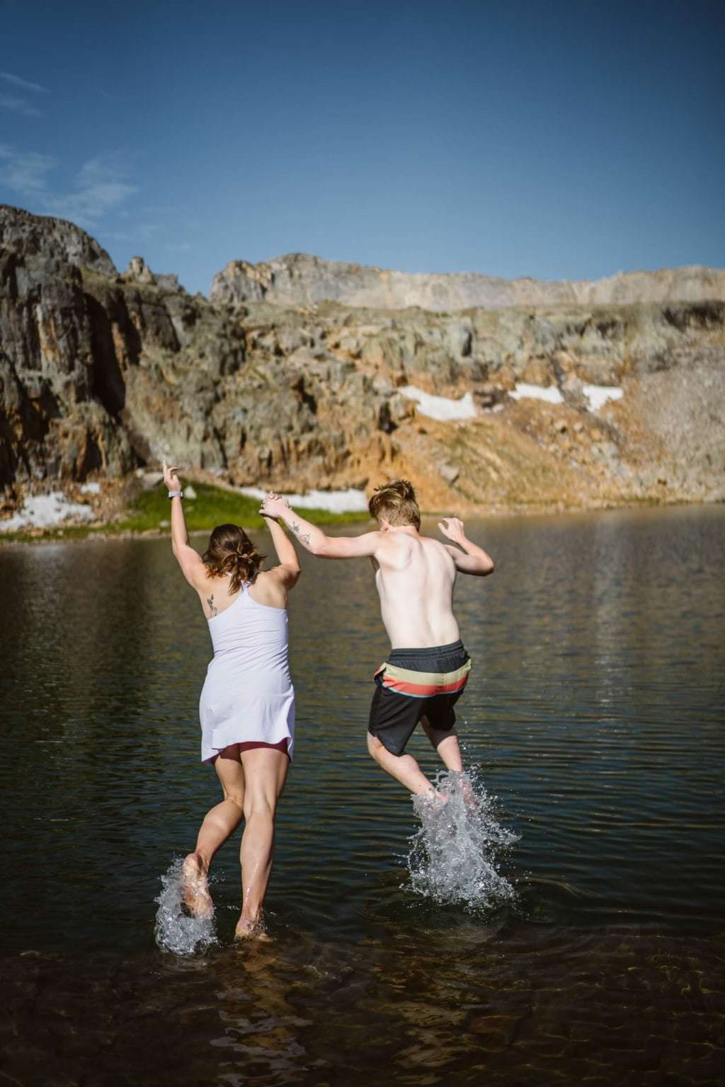 Couple jumping into an alpine lake.