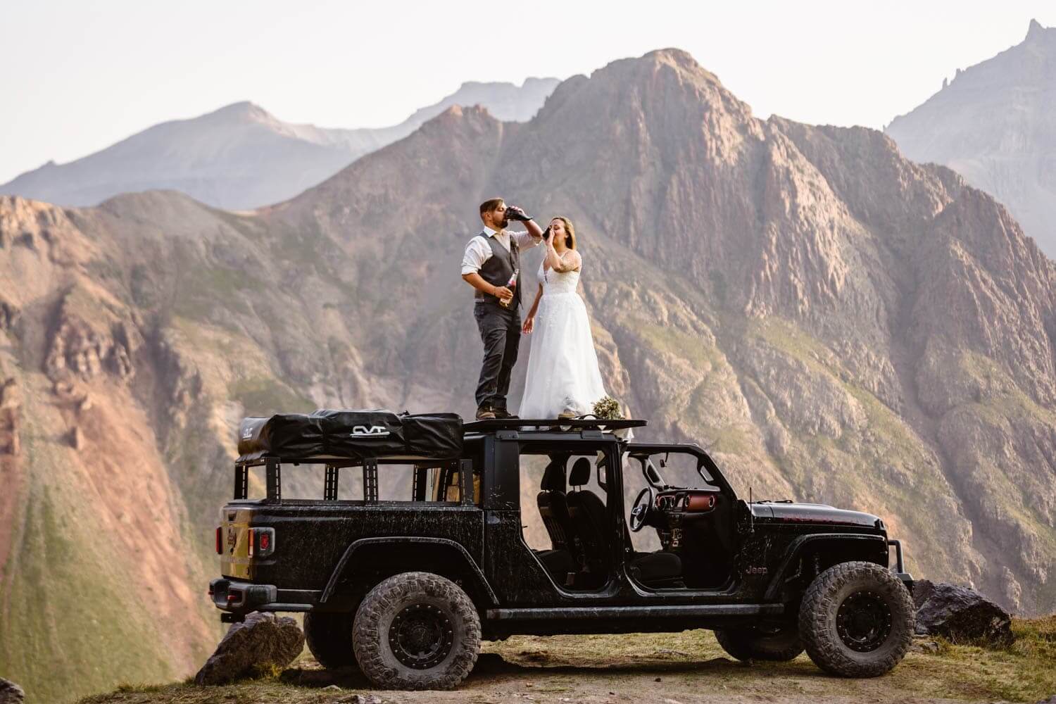 Couple celebrating drinks on top of a jeep at their off roading elopement.