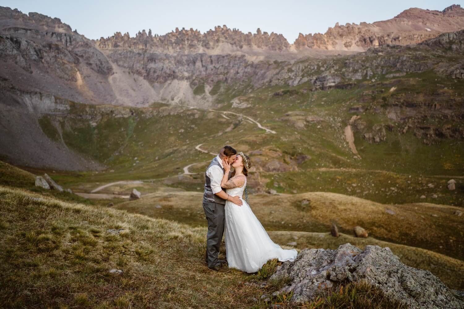 A couple sharing a kissing in their wedding attire in the mountains.