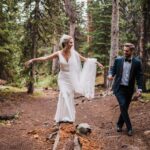 Bride walking on a log with her husband in Colorado.