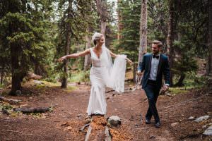 Bride walking on a log with her husband in Colorado.