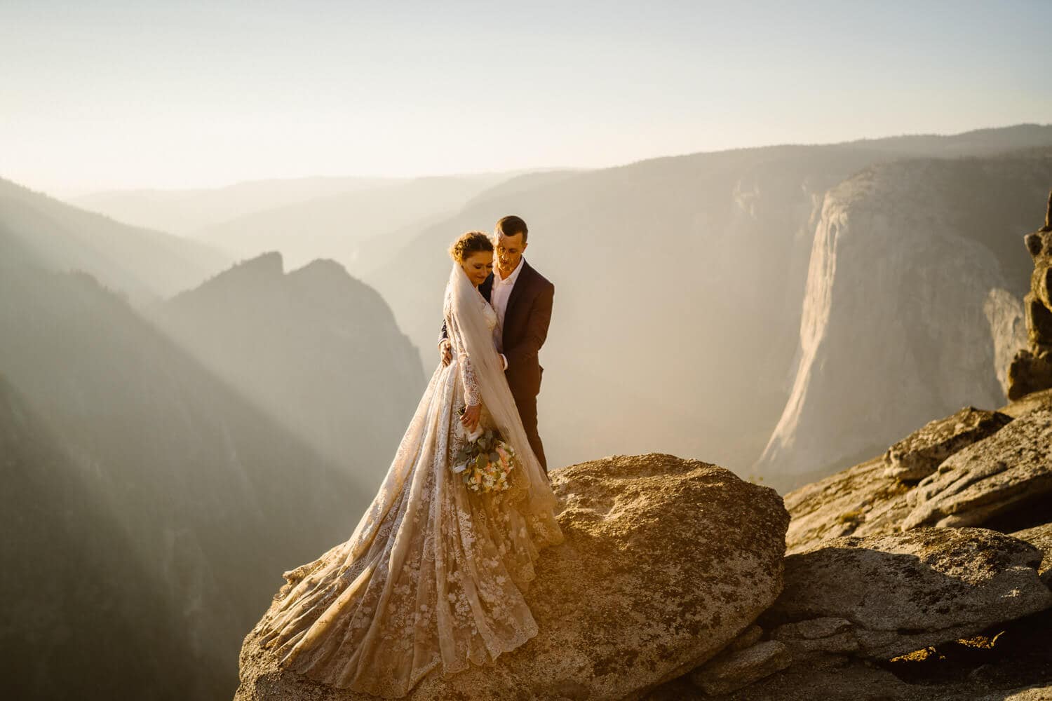A couple standing on a rock overlooking Taft Point for their wedding photos.