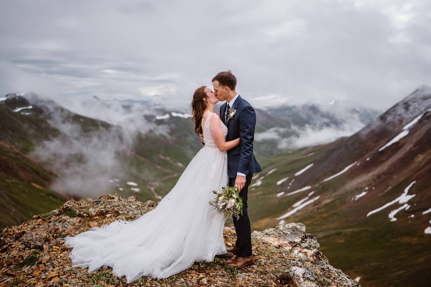Bride and groom sharing a kiss at sunrise on a mountain pass for their Telluride elopement.
