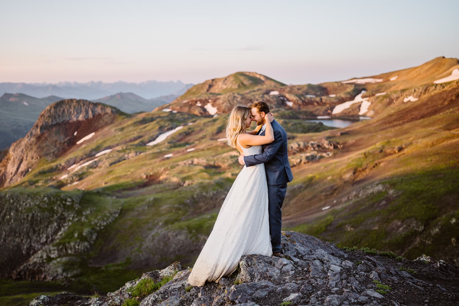 An elopement couple on a rock overlooking a mountain pass in Colorado.