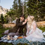 Couple sharing food at a picnic during their elopement in Colorado.
