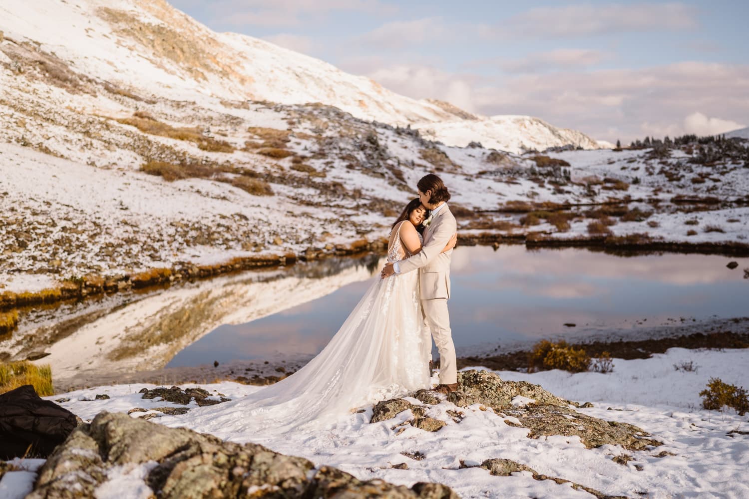 A couple who got married at sunrise in Colorado with an alpine lake in the background.