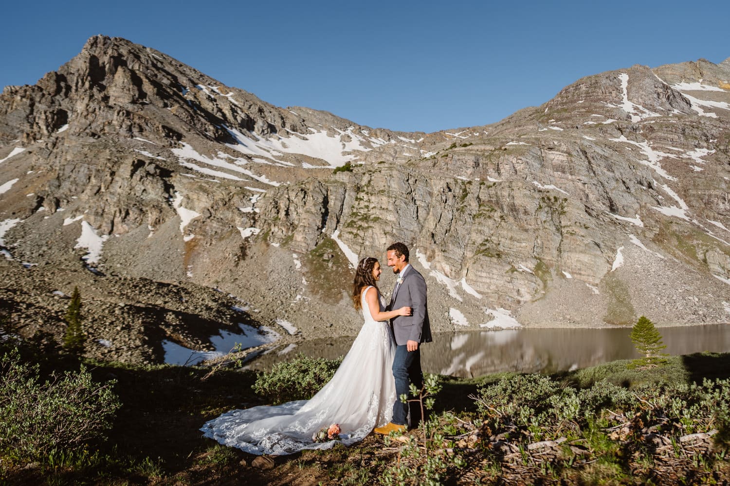 Bride and groom sharing a hug and laugh at an alpine lake in Colorado.