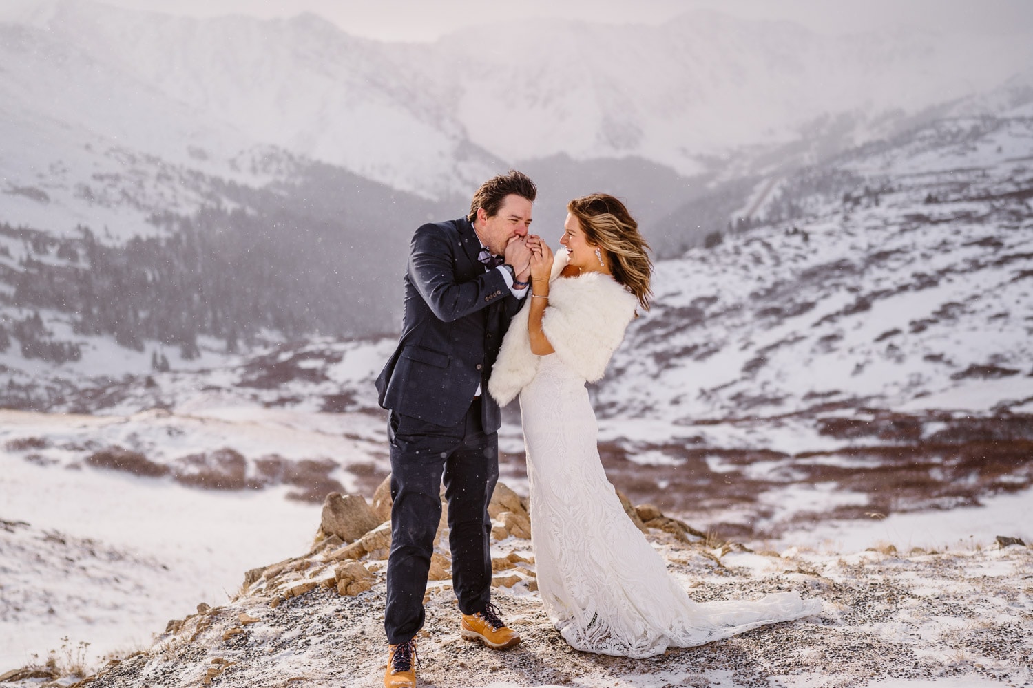 Couple sharing a laugh during a blizzard on top of a mountain in Colorado during the winter.