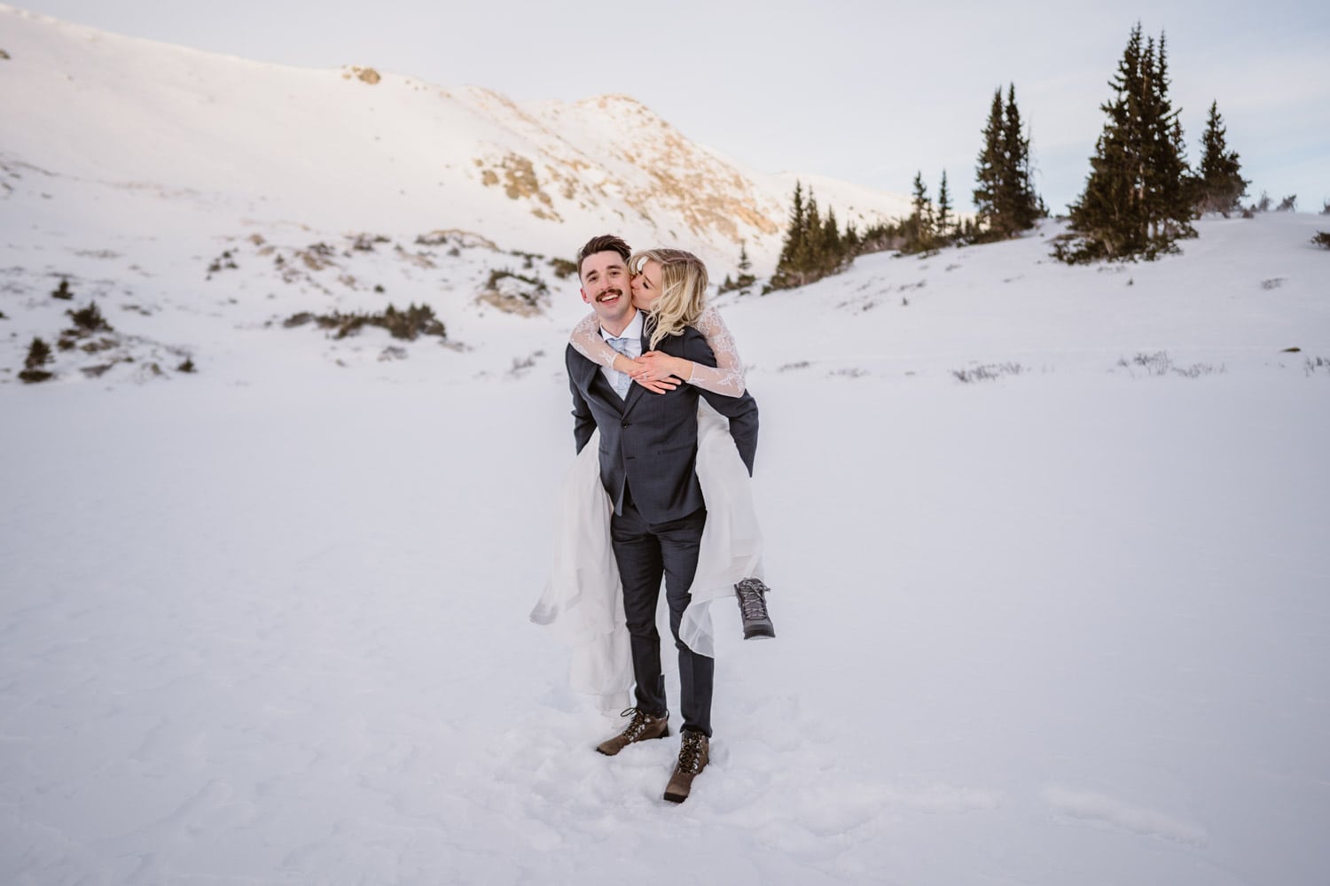 Bride on the grooms shoulder in the snow at sunrise in Colorado.