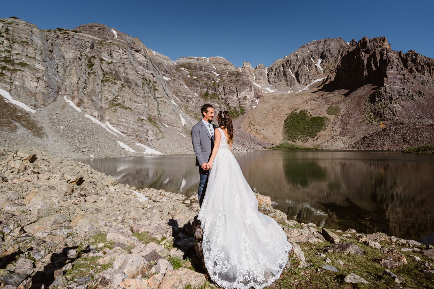 Couple standing on rock near a lake in Colorado on their elopement day.