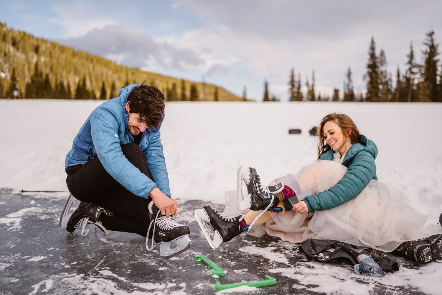 Bride and groom lacing up their ice skates on their wedding day in Colorado.
