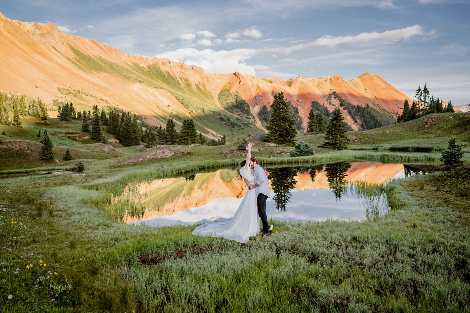 Bride lifting her hands up in celebration after getting married in the mountains.