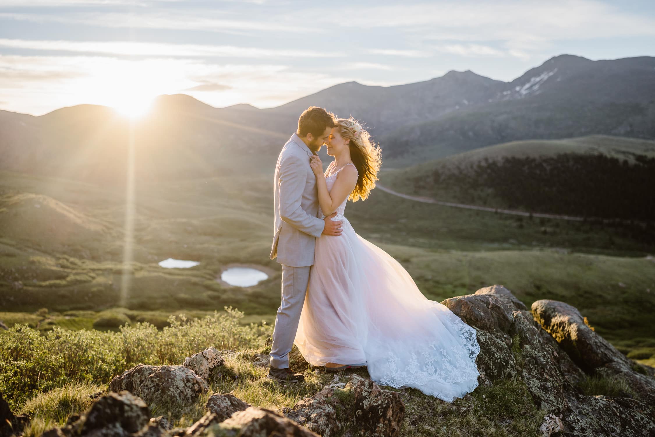 Bride and groom share a moment with the sun peaking over the mountain in the background.