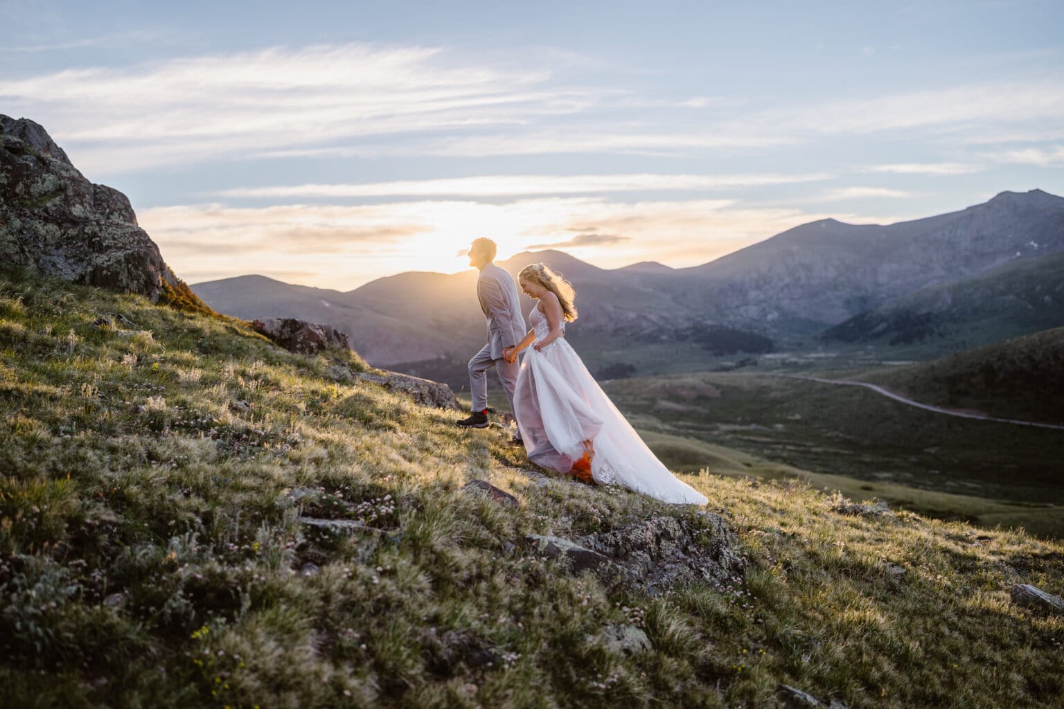 A bride and groom hiking up the tundra at sunrise on their elopement.