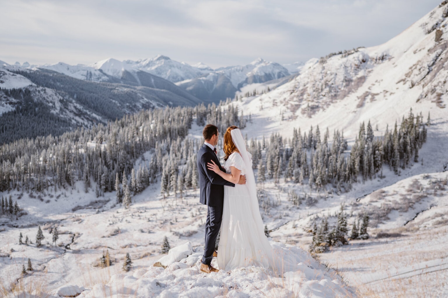 A couple overlooking a valley of snow for their winter elopement in Colorado.