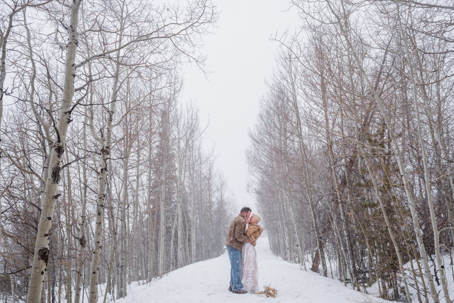 A couple sharing a kiss in the winter under some trees in Alma, Colorado.