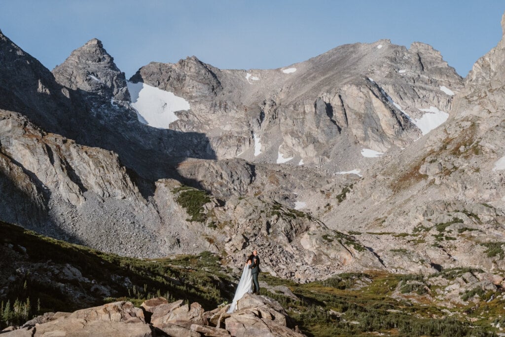 Couple standing below some mountains for their Lake Isabelle elopement.