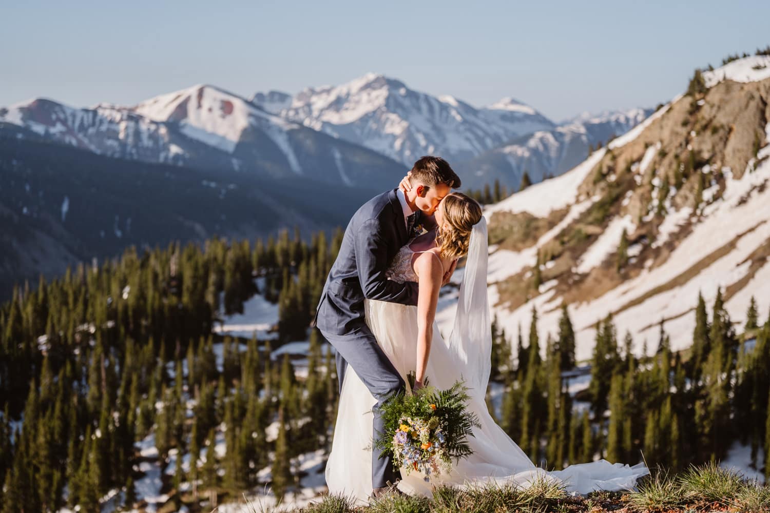 Groom dipping his wife down for a kiss in the mountains on their elopement in Colorado.