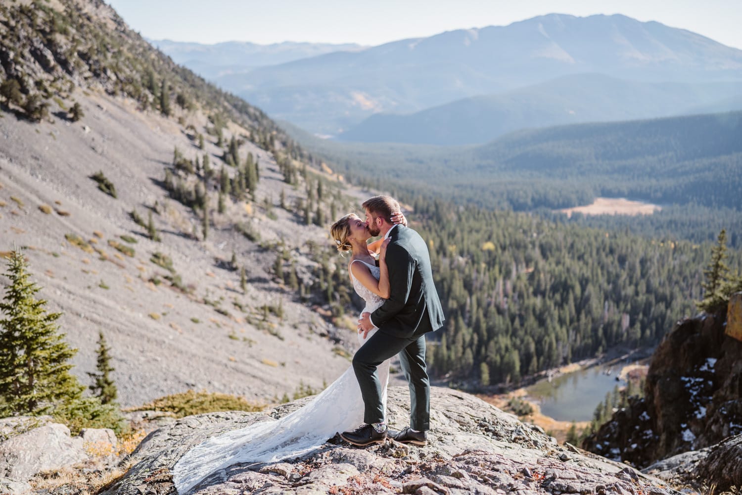 A bride and groom sharing a kiss at sunrise overlooking the mountains of Colorado.