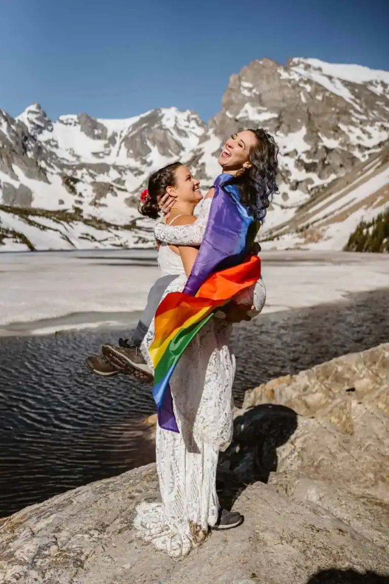 LGBTQ Elopement in Colorado Two brides dancing with their pride flag after their Colorado elopement