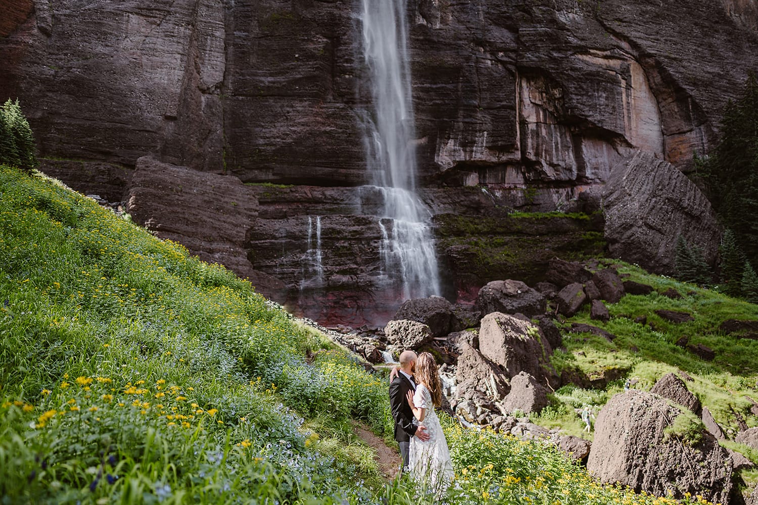 Couple standing beneath bridal veil falls in Telluride, Colorado for their elopement.