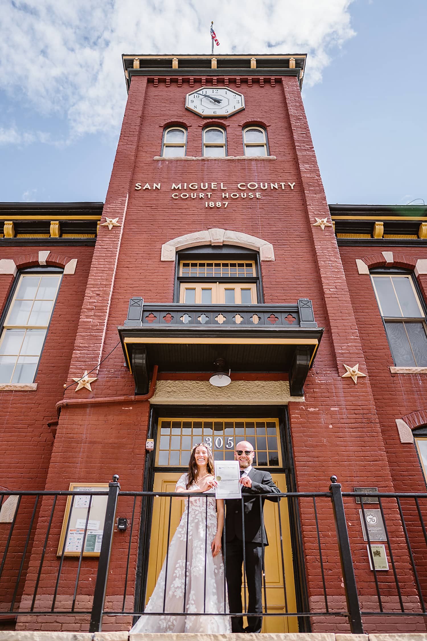A couple standing on the courthouse steps in Telluride with their marriage license.