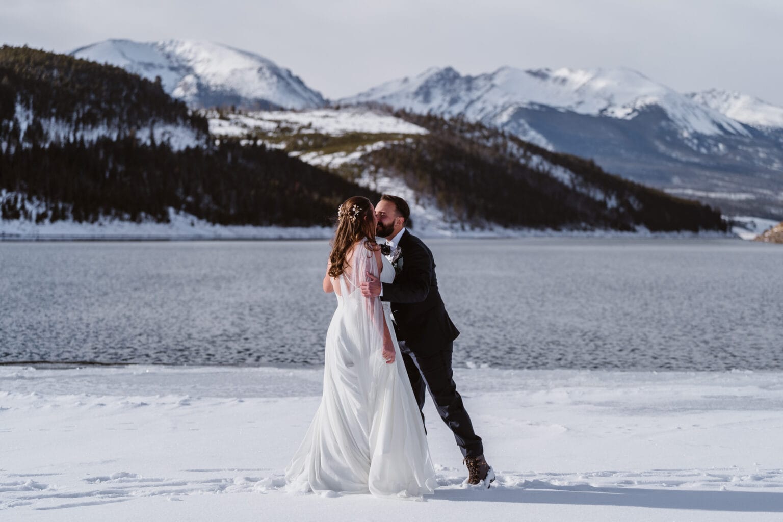 A couple sharing a kiss in the snow on a frozen lake in Colorado.