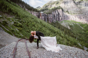 Groom dipping his wife for a kiss with bridal veil falls behind them in Telluride.