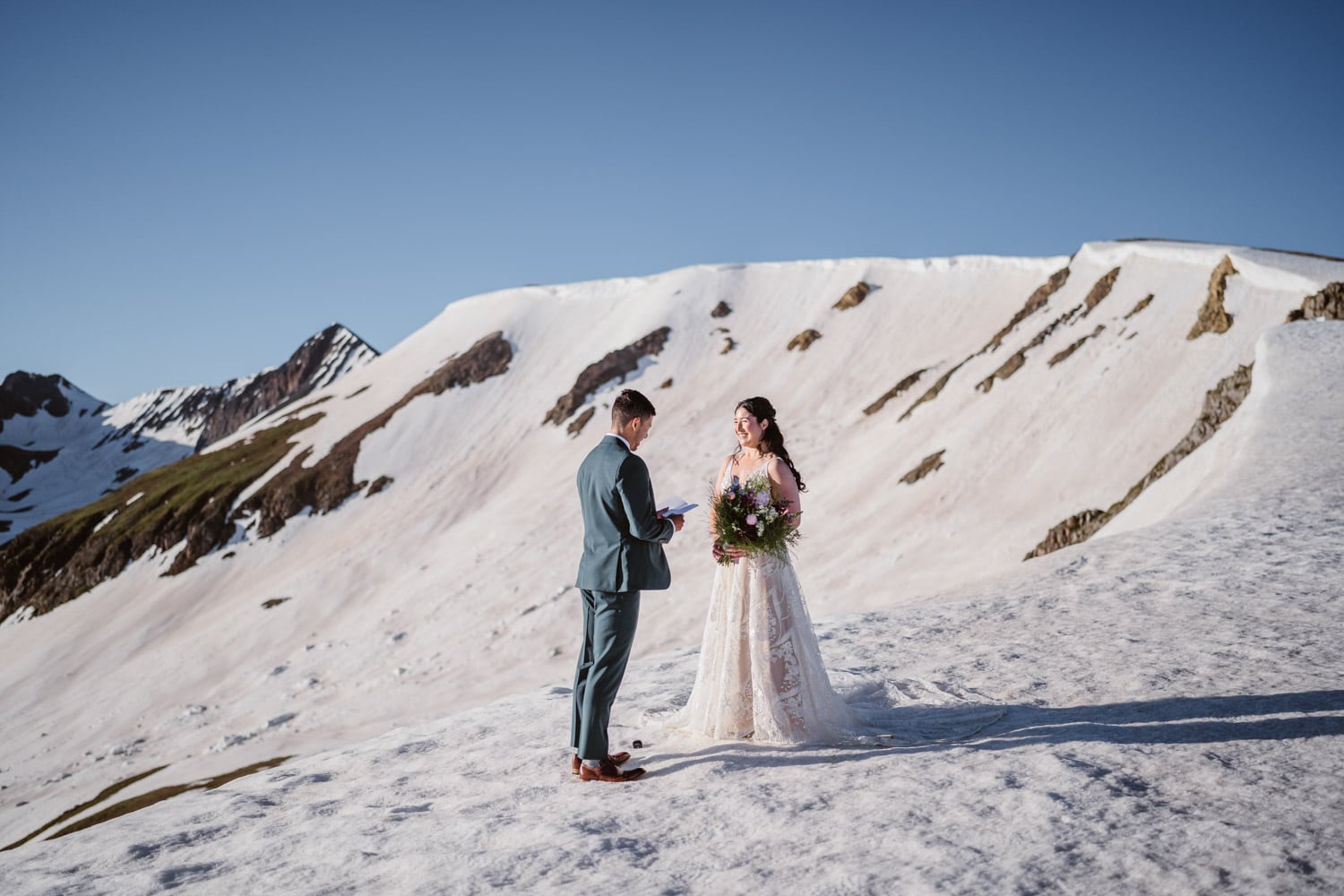 Couple standing on snow and ice sharing their vows at sunrise for their Colorado elopement.
