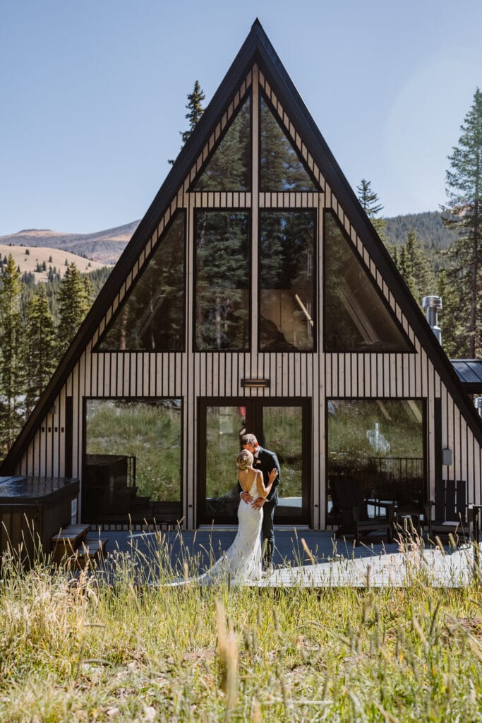 A couple sharing a kiss in front of their A frame cabin in Colorado during their Colorado elopement.