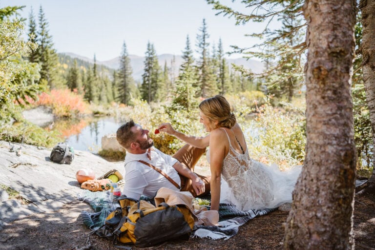 A couple sharing grapes at a picnic during their Colorado elopement.