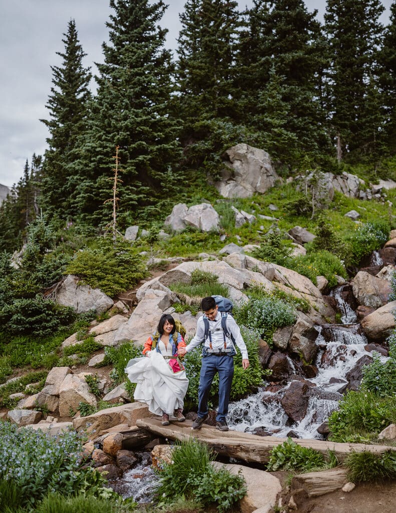 Couple hiking down near waterfall for their Lake Isabelle elopement.