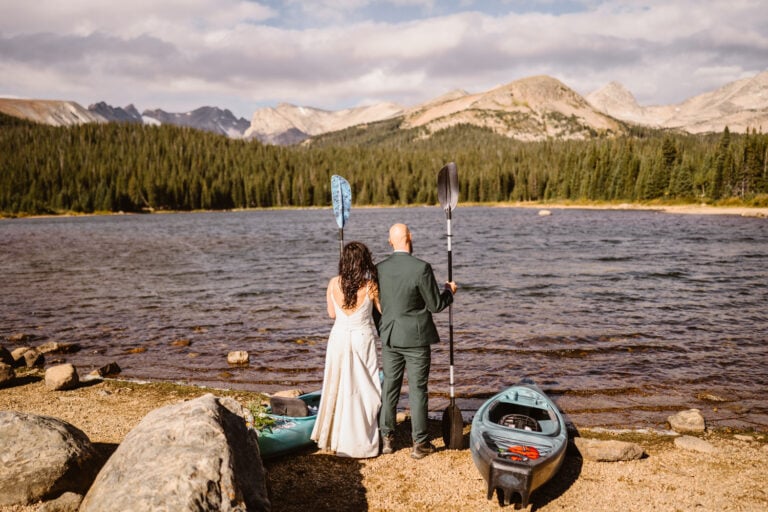 Couple standing near their paddle boards for their Lake Isabelle elopement.