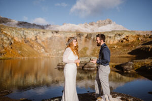 Couple sharing their vows near an alpine lake at sunrise in the fall in Colorado.