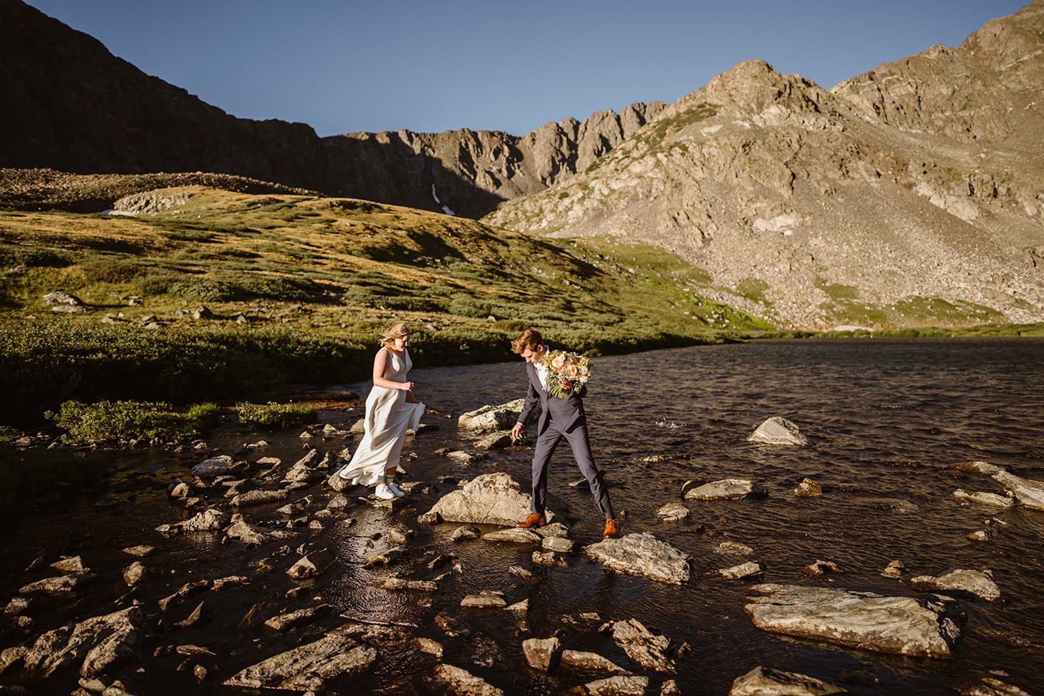 Bride and groom going over rocks at their off roading elopement.