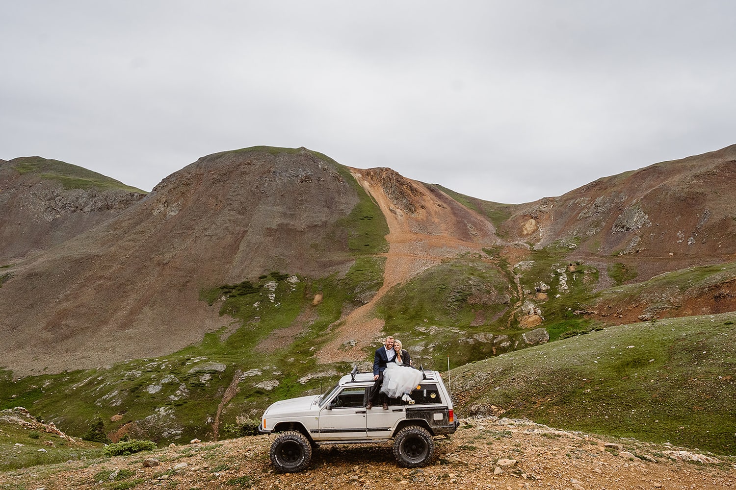 Bride and groom on top of their jeep at their off roading elopement.