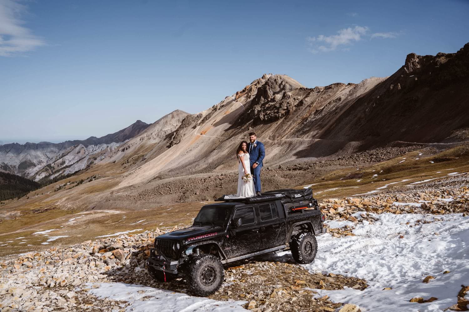 Bride and groom on top of a jeep at their off roading elopement.