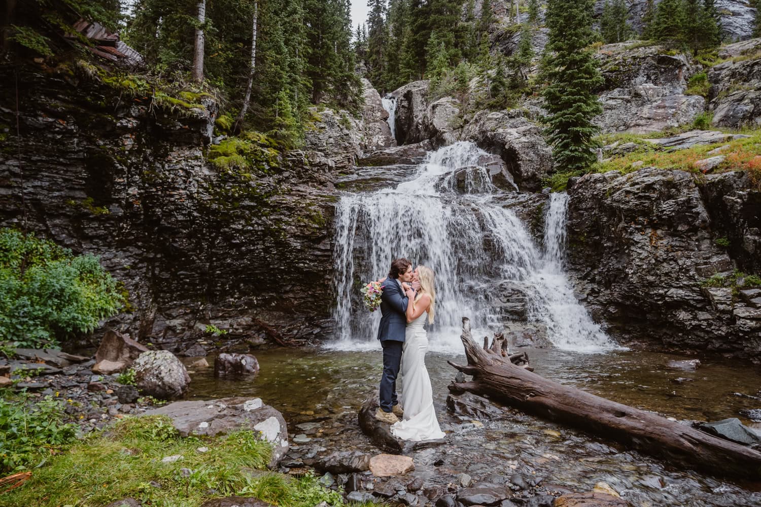 Couple sharing a kiss at a waterfall near Telluride for their elopement