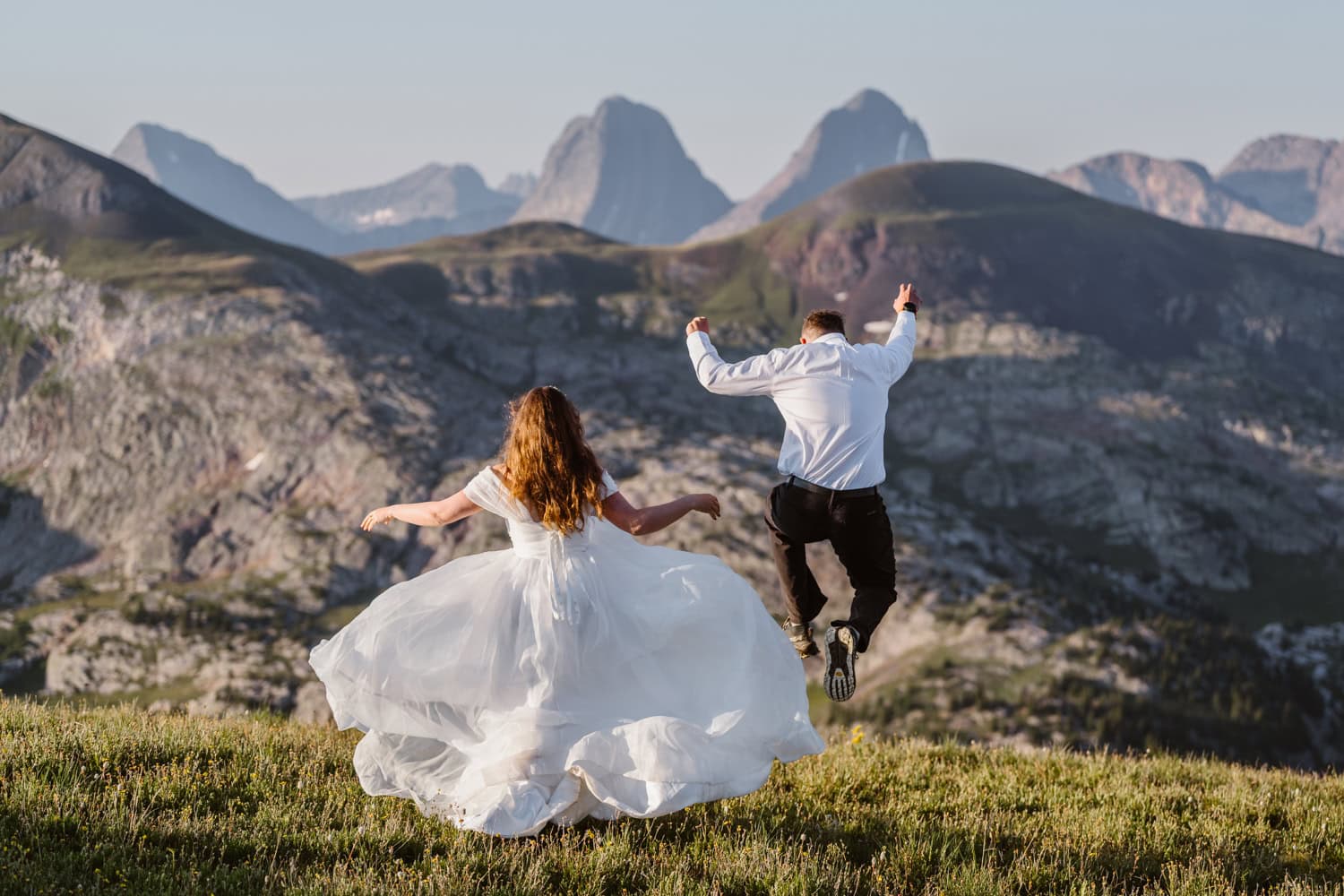 San Juan Mountain Colorado elopement Couple jumping on the grass celebrating for their elopement in Colorado.